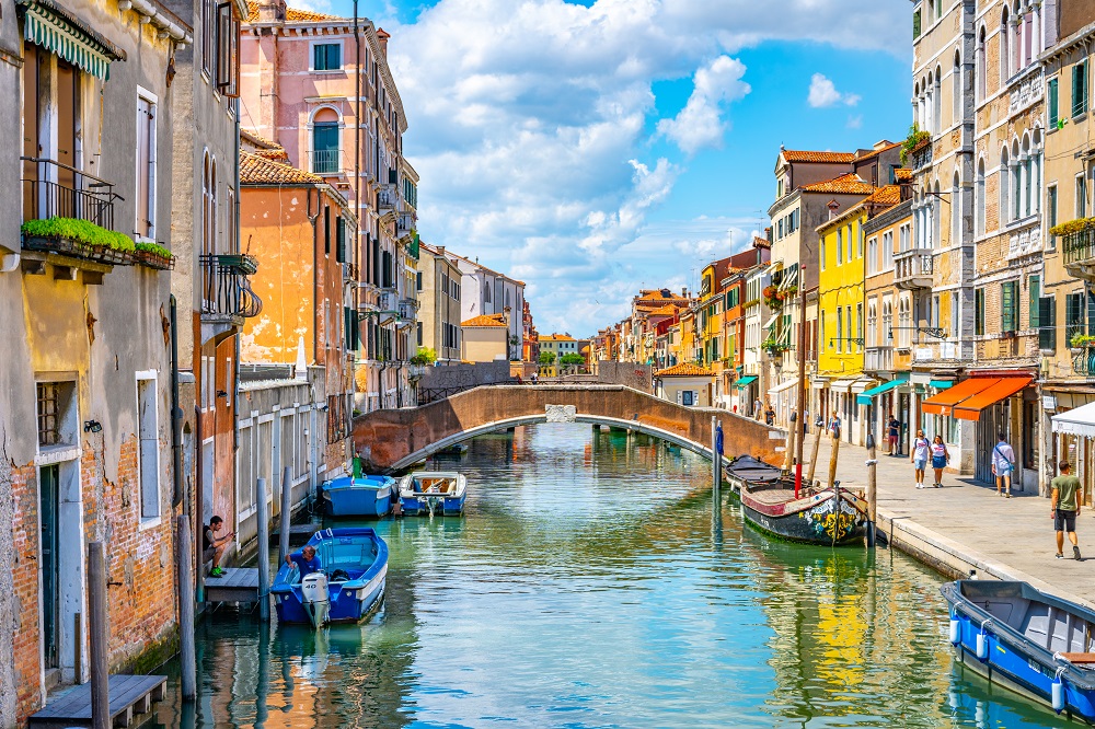 Widok na kanał w Wenecji, z łukowatymi mostami oraz kolorowymi kamienicami